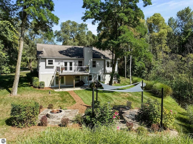 rear view of house featuring a lawn, a wooden deck, and a fire pit