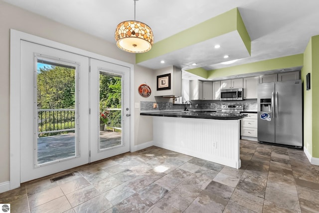 kitchen with sink, hanging light fixtures, tasteful backsplash, kitchen peninsula, and stainless steel appliances