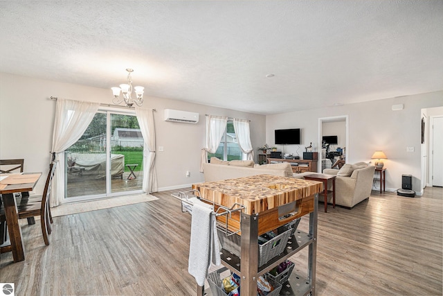 dining room featuring wood-type flooring, an AC wall unit, a wealth of natural light, and an inviting chandelier