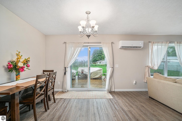 dining room featuring an AC wall unit, hardwood / wood-style flooring, a textured ceiling, and an inviting chandelier