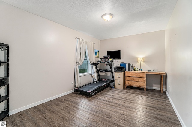 workout room with a textured ceiling and dark wood-type flooring