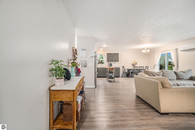 living room featuring a chandelier, light hardwood / wood-style flooring, and a wall mounted AC