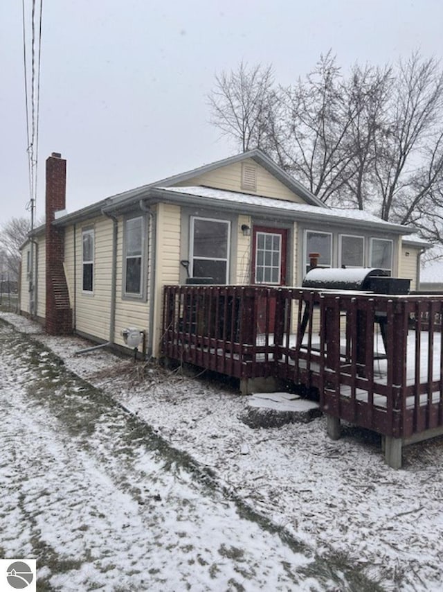 snow covered house with a wooden deck