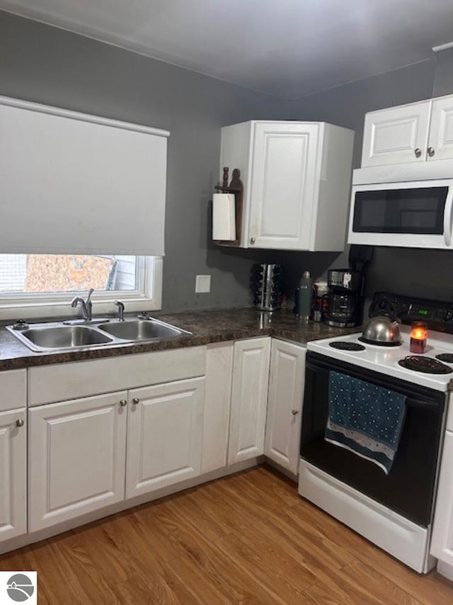 kitchen featuring electric range oven, light wood-type flooring, white cabinetry, and sink