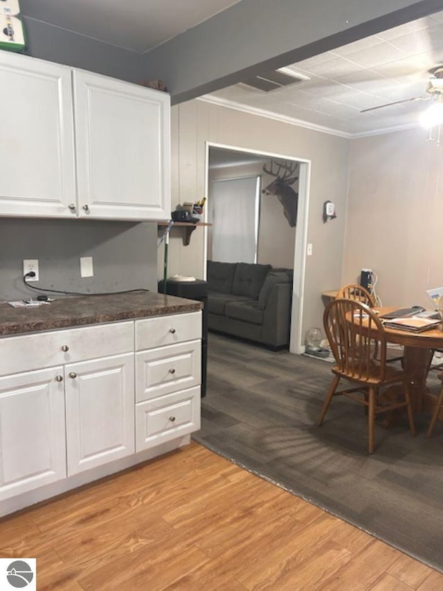 kitchen with white cabinetry, ceiling fan, ornamental molding, and light wood-type flooring