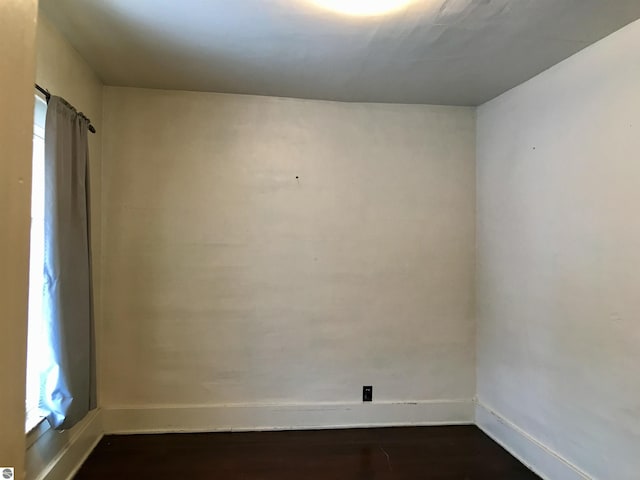 spare room with a wealth of natural light and dark wood-type flooring