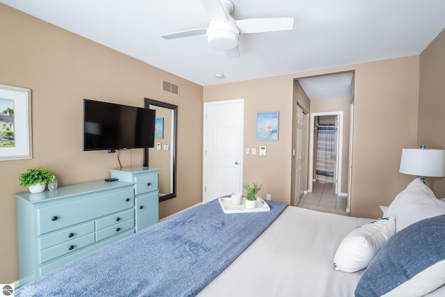 bedroom featuring ceiling fan, light tile patterned floors, and ensuite bath