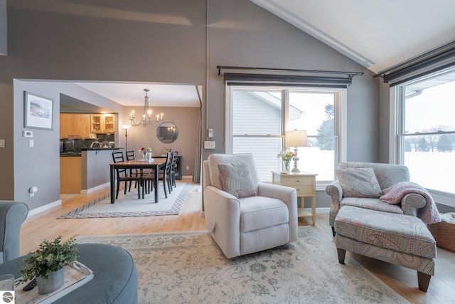 living room featuring a chandelier, light hardwood / wood-style floors, and lofted ceiling