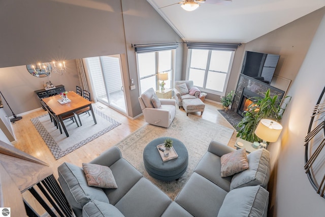 living room with hardwood / wood-style floors, ceiling fan with notable chandelier, vaulted ceiling, and a premium fireplace