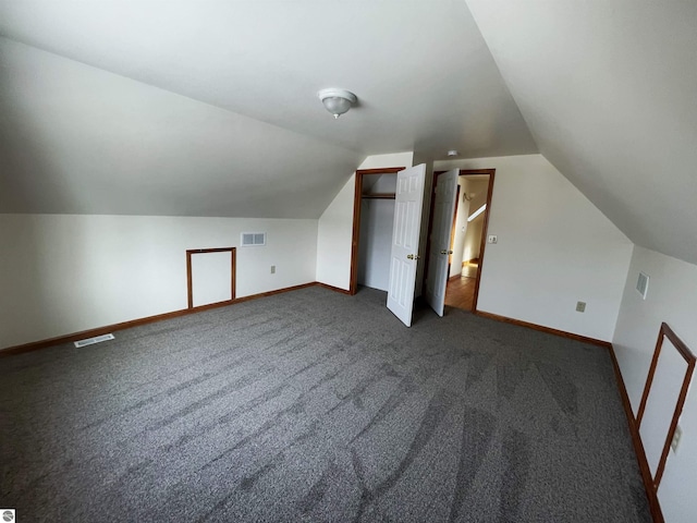 additional living space featuring dark carpet and lofted ceiling