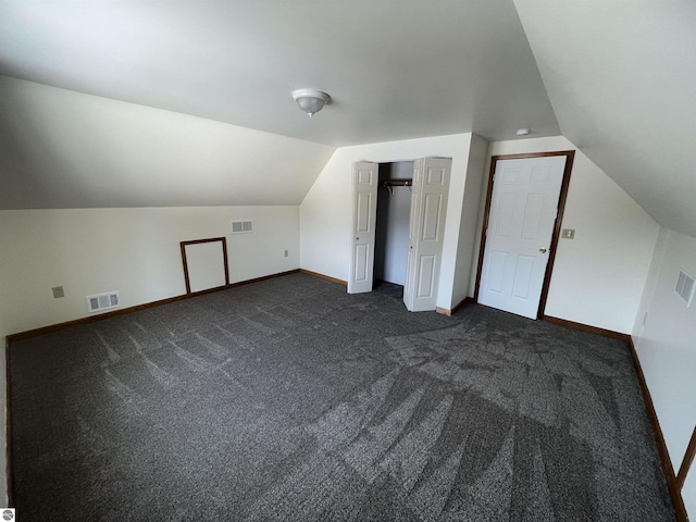 additional living space featuring dark carpet and vaulted ceiling