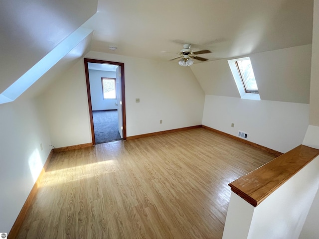 bonus room with ceiling fan, a healthy amount of sunlight, light hardwood / wood-style floors, and lofted ceiling with skylight