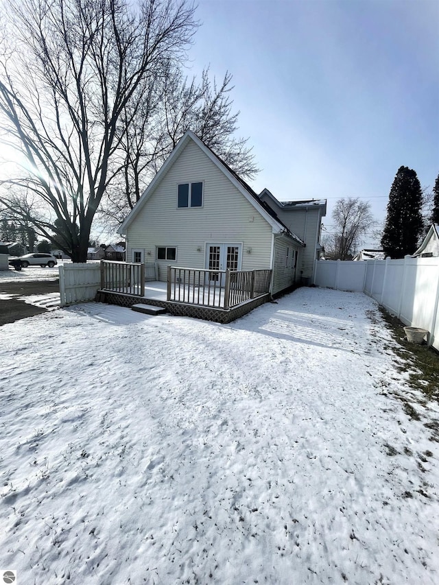 snow covered back of property featuring a wooden deck