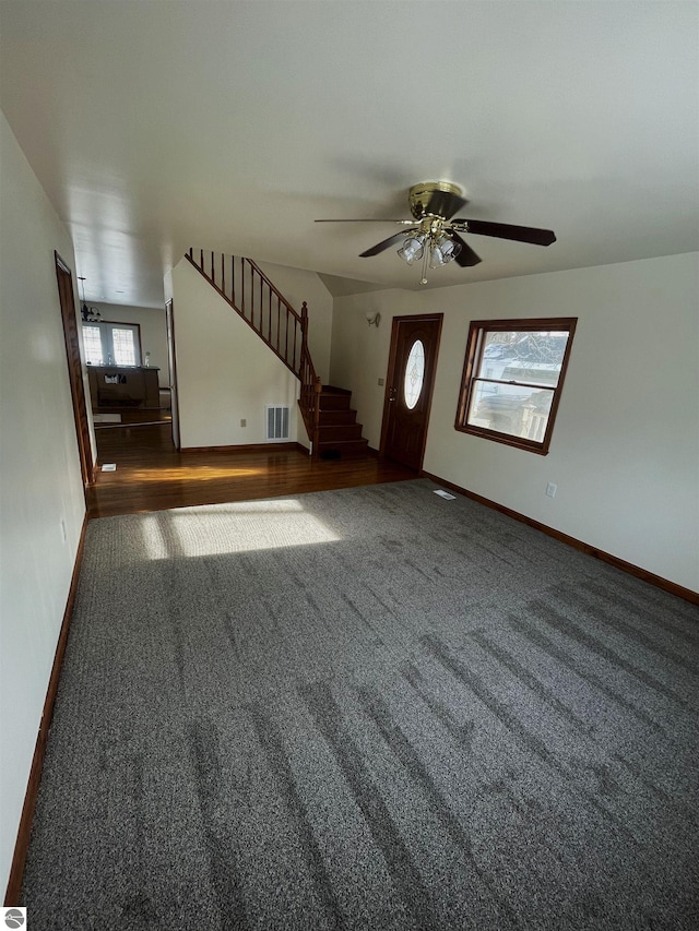 entrance foyer with ceiling fan and dark carpet