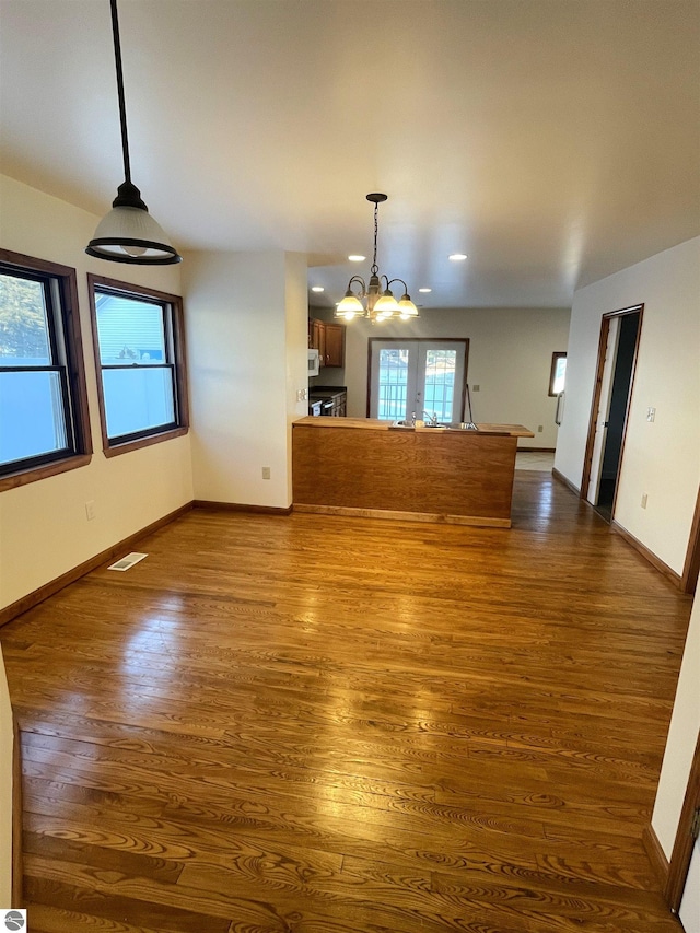 interior space with wood-type flooring, french doors, and a notable chandelier