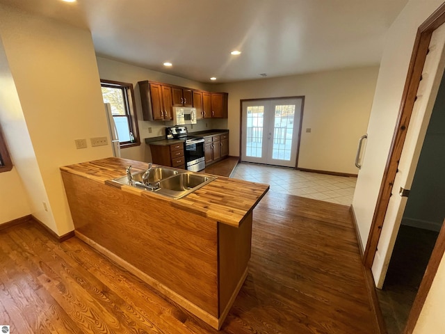 kitchen featuring stainless steel electric stove, kitchen peninsula, sink, and hardwood / wood-style flooring