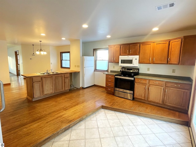 kitchen with white appliances, sink, decorative light fixtures, light tile patterned floors, and a notable chandelier