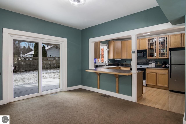 kitchen with electric stove, light carpet, sink, and stainless steel refrigerator