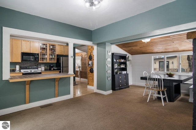 kitchen featuring dark colored carpet, wood ceiling, stainless steel refrigerator, electric stove, and a kitchen bar