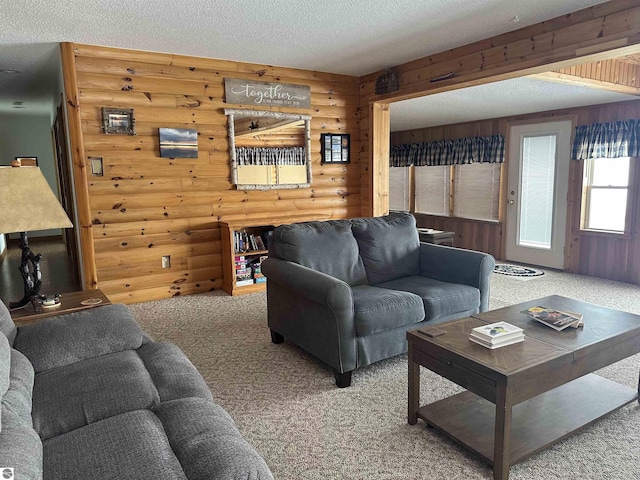 carpeted living room with log walls, a textured ceiling, and wood walls