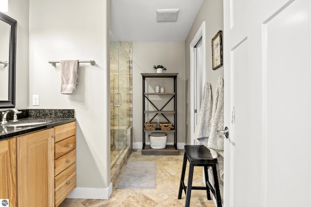 bathroom featuring a shower with door and vanity