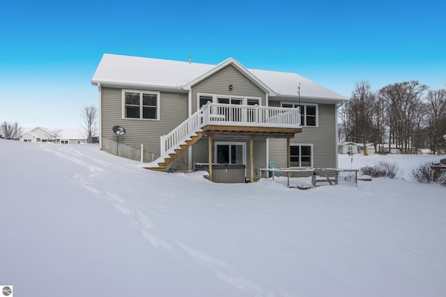 snow covered back of property with a deck