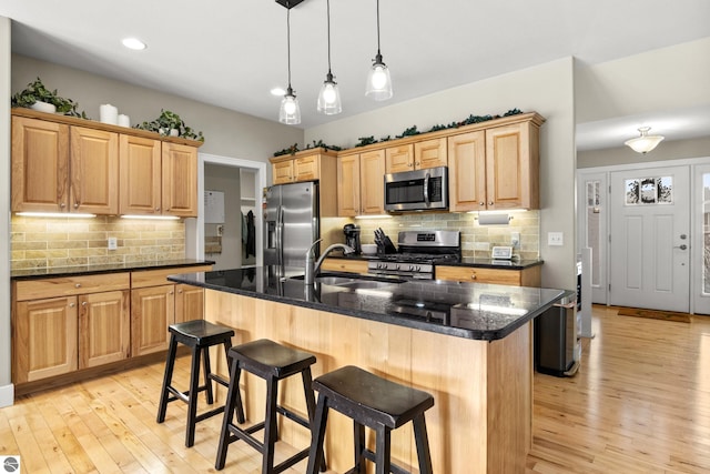 kitchen with appliances with stainless steel finishes, an island with sink, dark stone counters, and sink