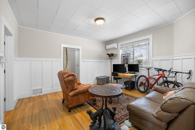 living room featuring an AC wall unit, light wood-type flooring, and crown molding