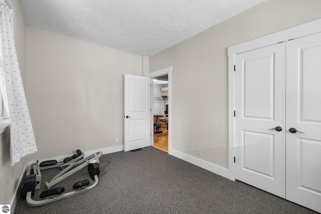 workout room with a textured ceiling and dark colored carpet