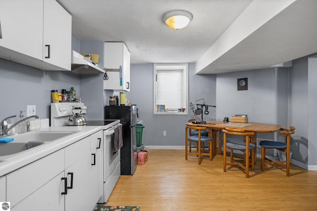 kitchen with white electric range oven, a textured ceiling, white cabinets, light hardwood / wood-style flooring, and sink