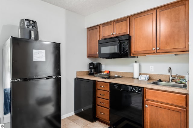 kitchen featuring a textured ceiling, black appliances, light tile patterned floors, and sink