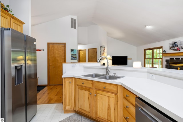 kitchen featuring sink, light tile patterned floors, vaulted ceiling, and stainless steel appliances