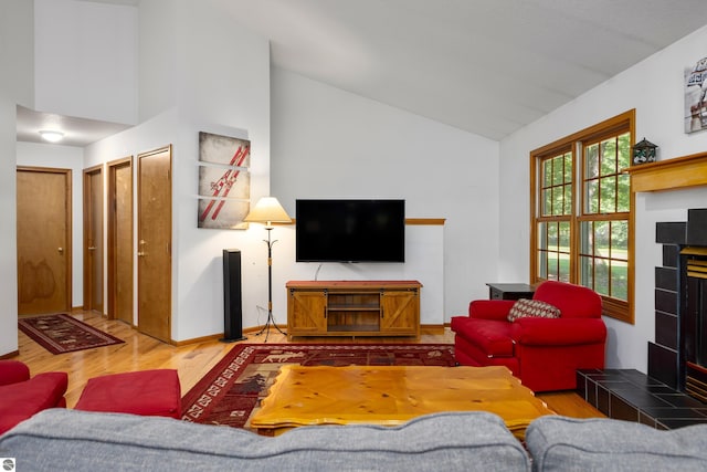 living room featuring hardwood / wood-style flooring, high vaulted ceiling, and a tile fireplace