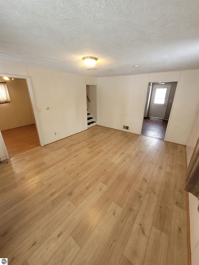 empty room featuring a textured ceiling and light hardwood / wood-style flooring