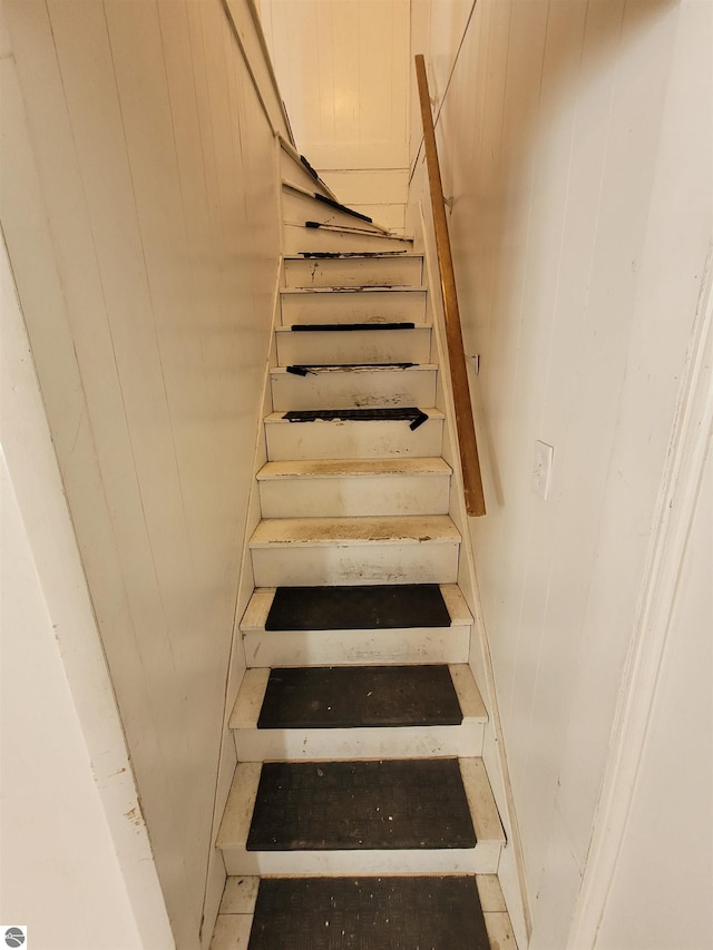 staircase featuring wood walls