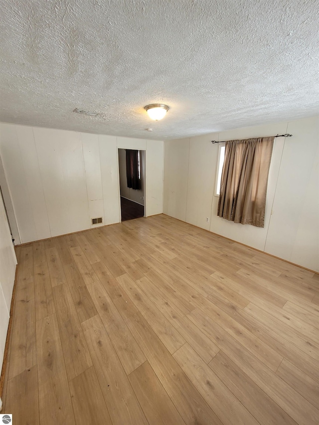 unfurnished room featuring a textured ceiling and light hardwood / wood-style flooring