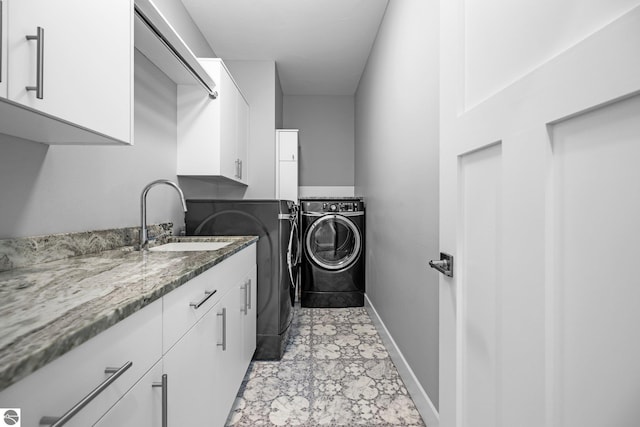 clothes washing area featuring washer and dryer, cabinets, and sink