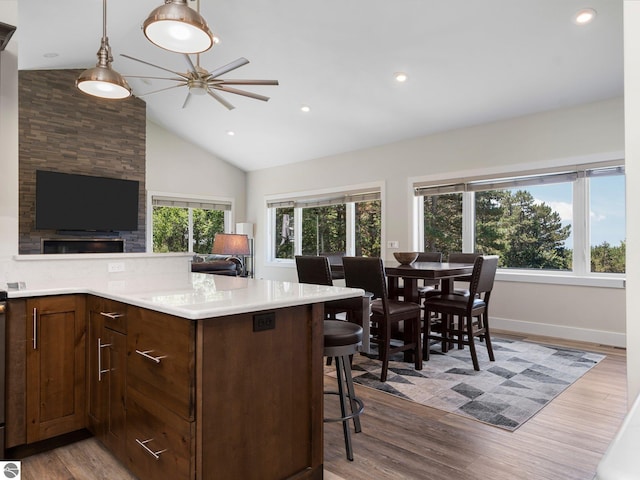 kitchen featuring light hardwood / wood-style floors, a breakfast bar, vaulted ceiling, and ceiling fan