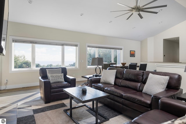 living room featuring ceiling fan, light hardwood / wood-style flooring, and vaulted ceiling