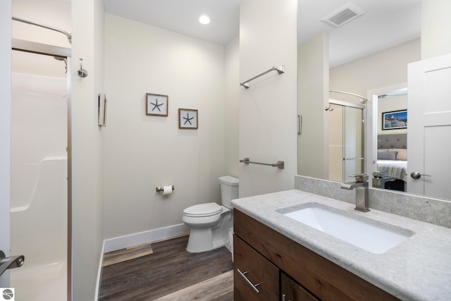 bathroom with hardwood / wood-style floors, an enclosed shower, vanity, and toilet