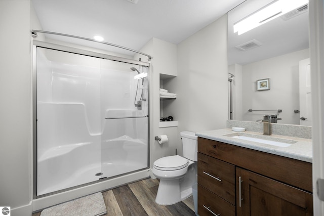 bathroom with vanity, toilet, a shower with shower door, and wood-type flooring