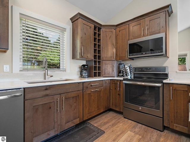 kitchen featuring sink, vaulted ceiling, light hardwood / wood-style flooring, and appliances with stainless steel finishes