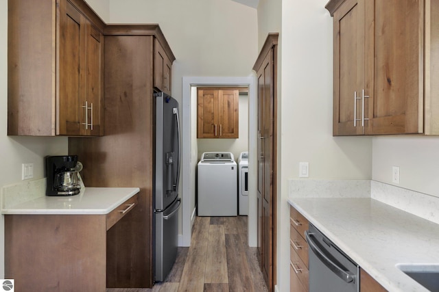 kitchen with appliances with stainless steel finishes, dark wood-type flooring, and washer and clothes dryer