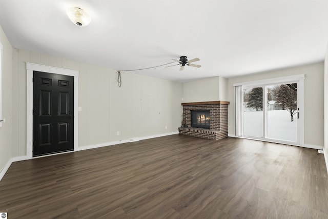 unfurnished living room with dark hardwood / wood-style flooring, a brick fireplace, and ceiling fan