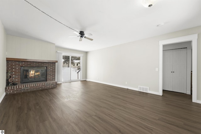 unfurnished living room with ceiling fan, dark wood-type flooring, and a brick fireplace