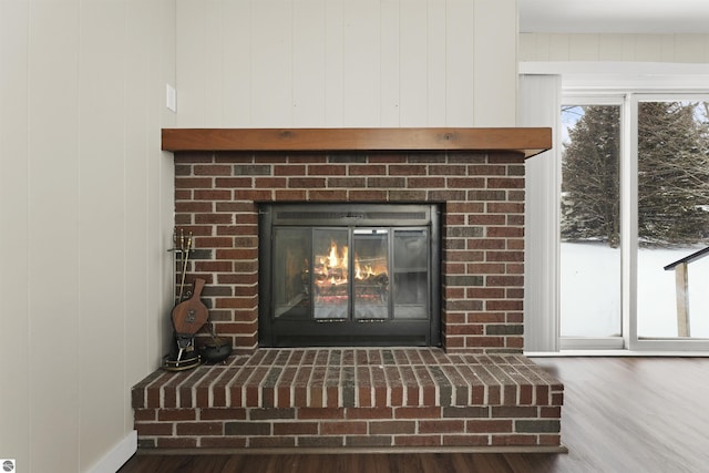 details with a brick fireplace, wooden walls, and wood-type flooring