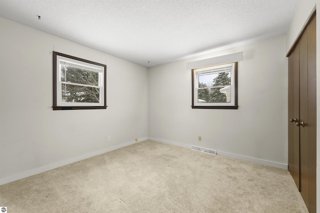 carpeted spare room with a textured ceiling