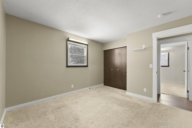 unfurnished bedroom with a textured ceiling, a closet, and carpet floors