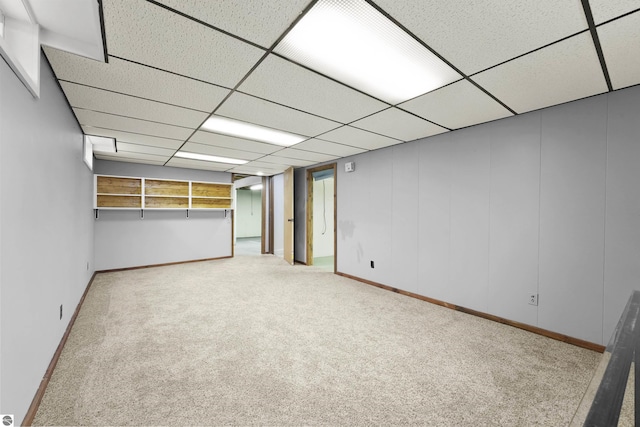 basement with a paneled ceiling and light carpet