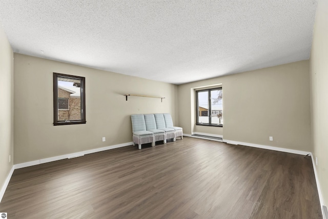 spare room featuring dark hardwood / wood-style flooring, a textured ceiling, and baseboard heating